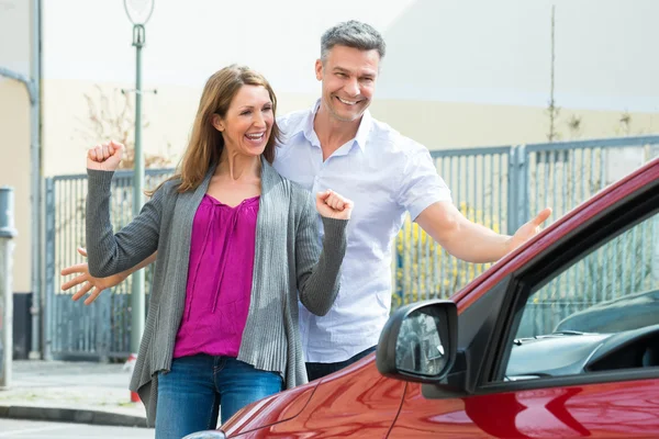 Pareja de pie en frente de coche nuevo — Foto de Stock