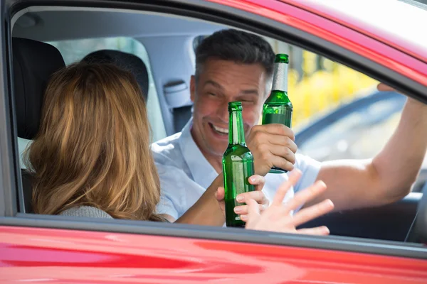 Pareja sentada dentro del coche disfrutando de la cerveza — Foto de Stock