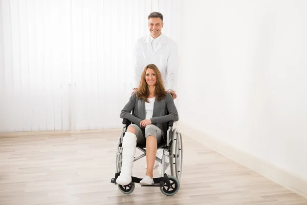 Médico asistiendo a la mujer en silla de ruedas — Foto de Stock