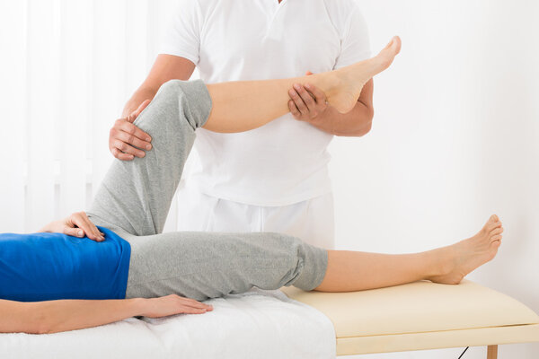 Masseur Giving Leg Massage To Woman