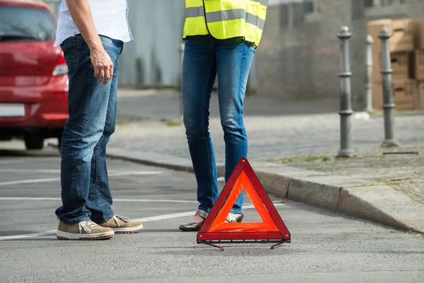 Ζευγάρι στέκεται κοντά τριγωνικό σημάδι προειδοποίησης — Φωτογραφία Αρχείου