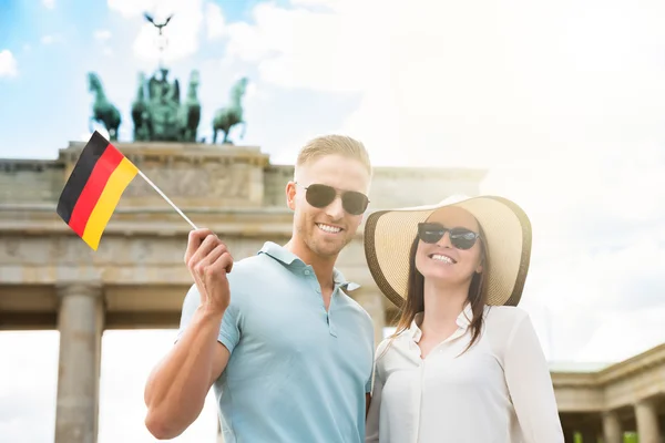 Pareja feliz sosteniendo bandera alemana — Foto de Stock