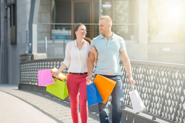 Pareja caminando en el puente con bolsas de compras — Foto de Stock