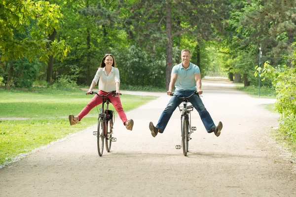 Feliz casal equitação bicicleta no parque — Fotografia de Stock