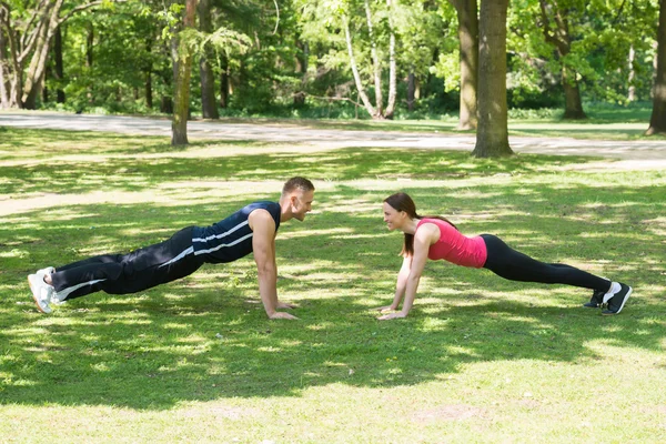 Pareja haciendo flexiones en el parque — Foto de Stock