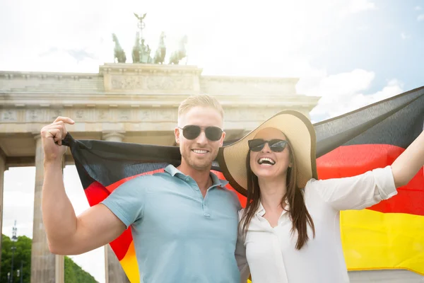 Usmívající se pár drží Německá vlajka — Stock fotografie