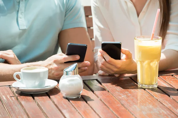 Casal sentado no banco usando telefone móvel — Fotografia de Stock