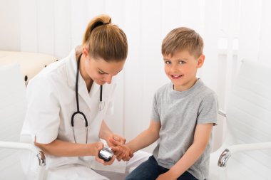 Doctor Examining Blood Sugar Of Little Boy clipart