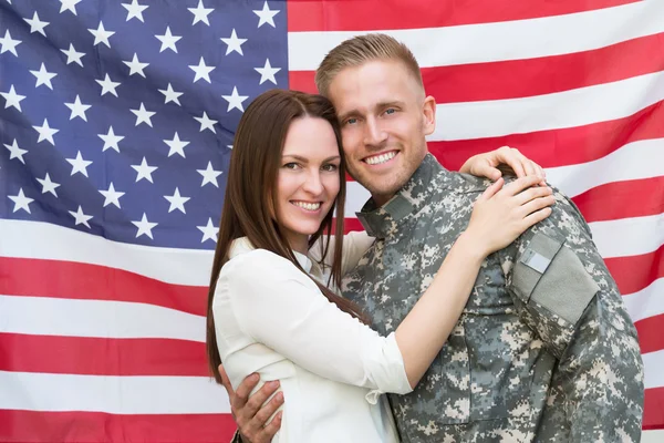 Mužské voják se svou ženou před americkou vlajkou — Stock fotografie