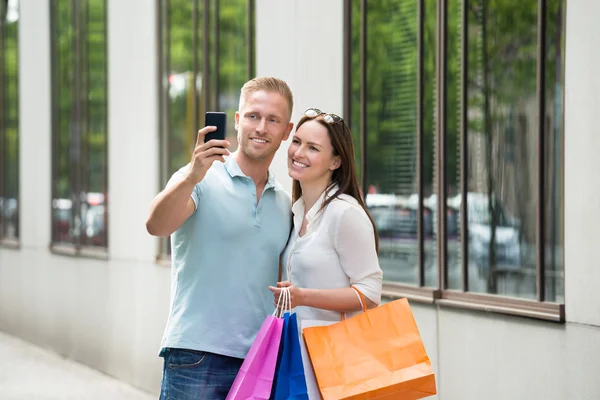 Couple avec sac à provisions prenant des photos dans Smartphone — Photo