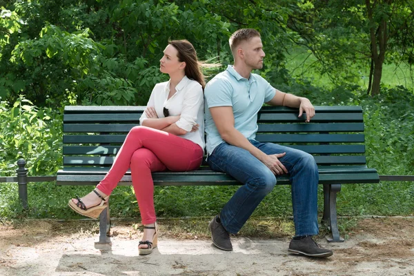 Пара сидящих спиной к спине на скамейке — стоковое фото