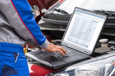 Makinist araba motoru incelenmesi için dizüstü bilgisayar kullanarak