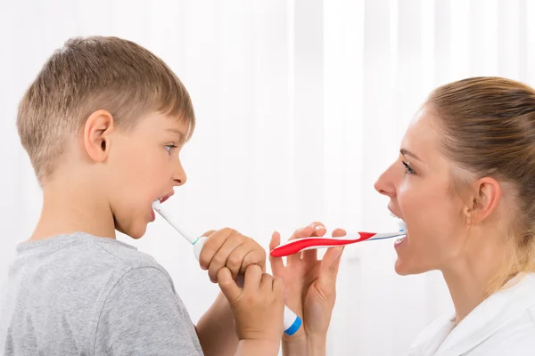 Доктор и мальчик чистят зубы — стоковое фото