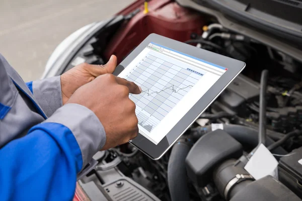 Mécanicien avec tablette numérique tout en examinant la voiture — Photo