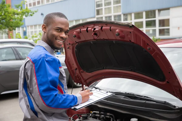 Mechaniker mit Klemmbrett vor einem Auto — Stockfoto
