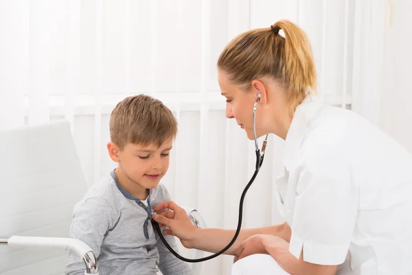 Médecin examinant garçon en clinique — Photo