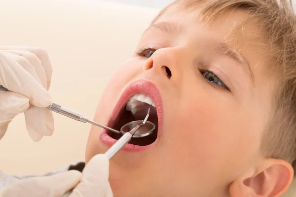 La mano del dentista examinando los dientes del paciente infantil — Foto de Stock