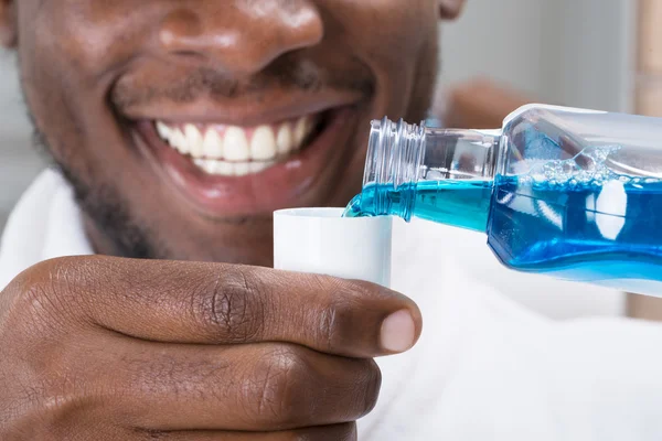 Mann schüttet Mundwasser in Mütze — Stockfoto