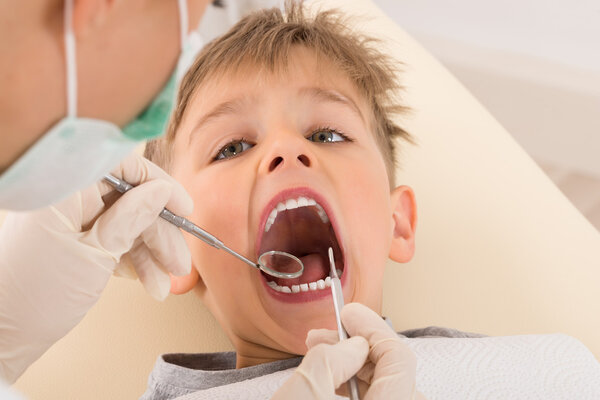 Dentist 's Hand Examining Teeth Of Child Patient
