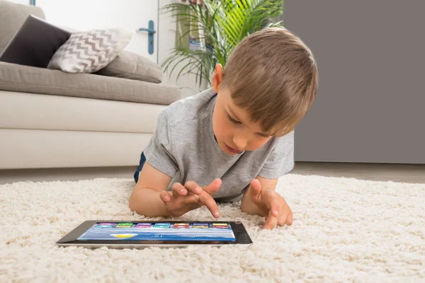Junge liegt mit digitalem Tablet auf Teppich — Stockfoto
