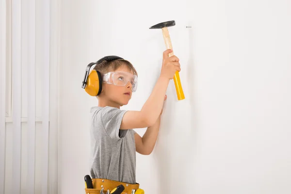 Chico martillando clavo en pared —  Fotos de Stock