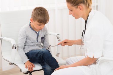 Doctor Checking Knee Reflex On Child Patient clipart