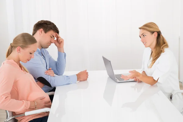 Doutor Consolando Casal Jovem Esperando Bebê — Fotografia de Stock