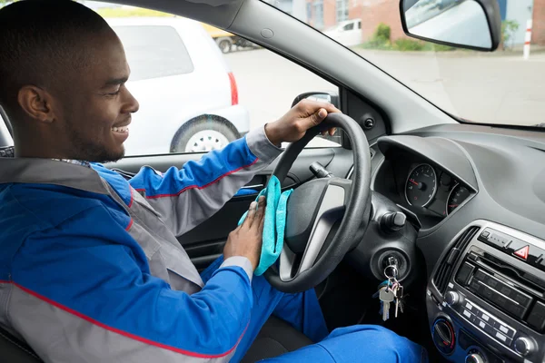 Werknemer stuurwiel van auto met doek schoonmaken — Stockfoto