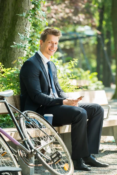 Zakenman zittend op de Bank met behulp van mobiele telefoon — Stockfoto