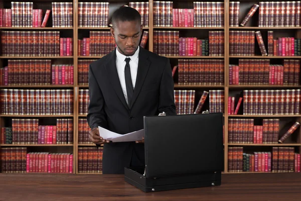 Anwalt mit Papieren und Aktentasche am Schreibtisch — Stockfoto