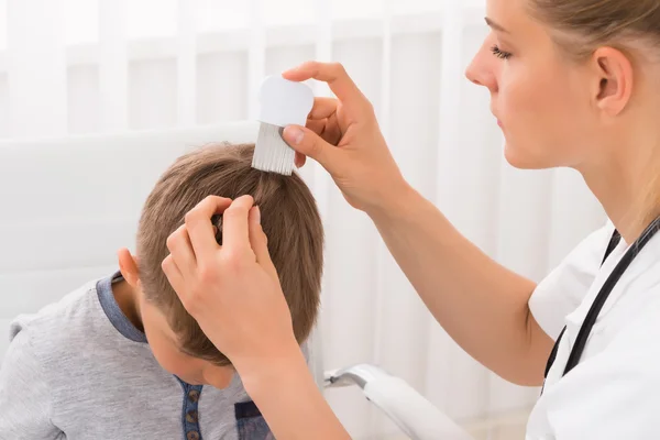 Médico fazendo tratamento no cabelo do menino — Fotografia de Stock