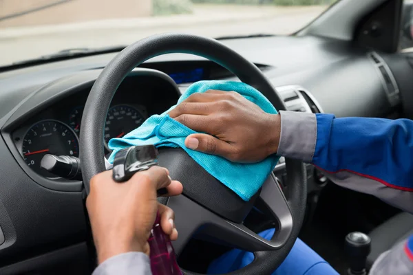 Trabajador limpiando el volante en el coche —  Fotos de Stock