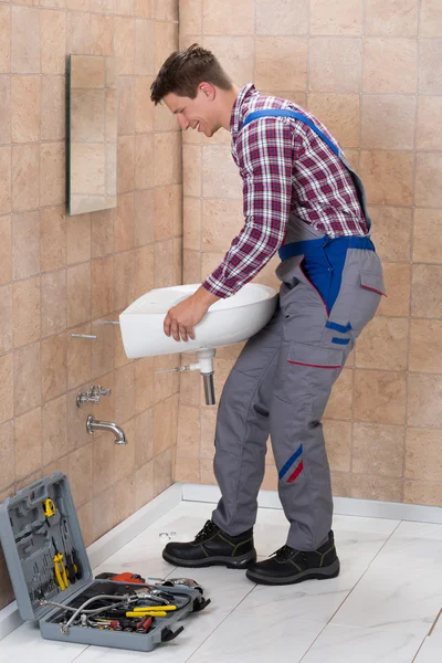 Encanador masculino instalando o dissipador no banheiro — Fotografia de Stock