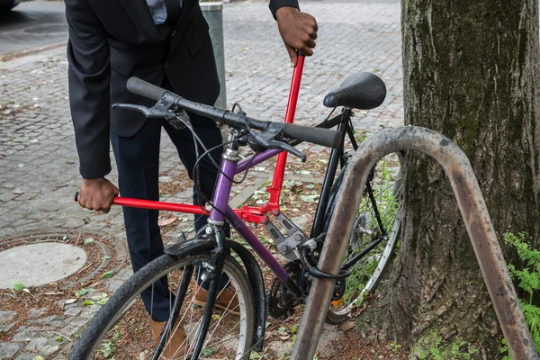 Ladrão tentando quebrar a fechadura da bicicleta — Fotografia de Stock