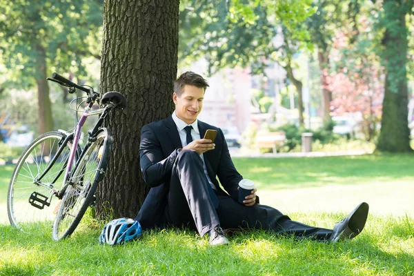 Biznesmen mężczyzna siedzi w parku — Zdjęcie stockowe