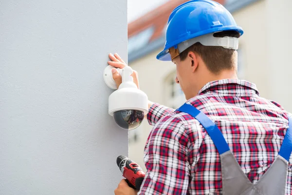 Jeune technicien masculin installant la caméra sur le mur — Photo