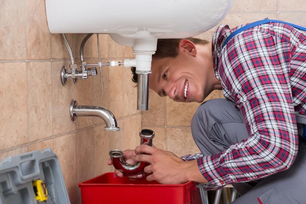 Klempner installiert Spülrohr im Badezimmer — Stockfoto