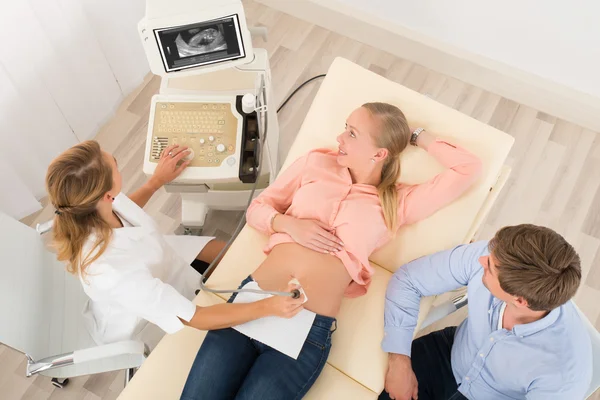 Médico que move a sonda de ultra-som no estômago da mulher grávida — Fotografia de Stock