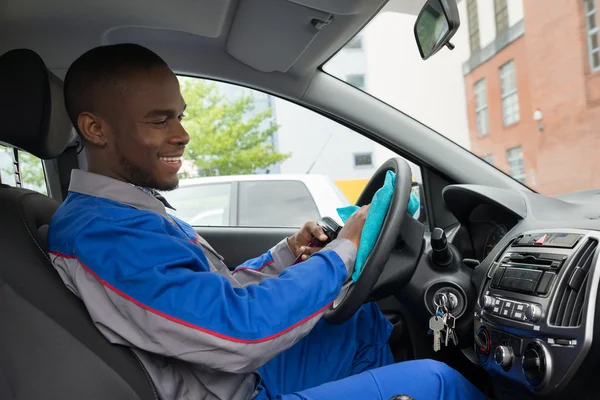 Werknemer stuurwiel van auto met doek schoonmaken — Stockfoto