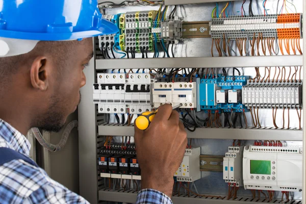 Electricista examinando caja de fusibles con destornillador — Foto de Stock