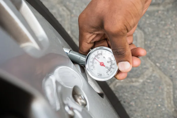 タイヤの空気圧を測定するためのゲージを保持している人 — ストック写真