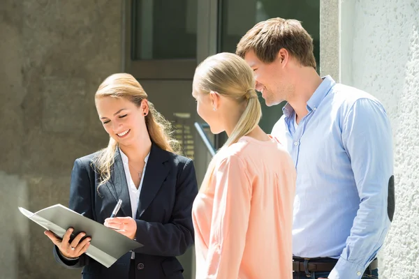 Immobilienmakler erklärt Paar Vertrag — Stockfoto