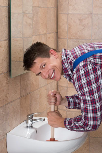 Férfi vízvezeték-szerelő segítségével dugattyút mosogató — Stock Fotó