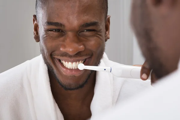 Africano hombre limpieza su dientes en frente de espejo — Foto de Stock