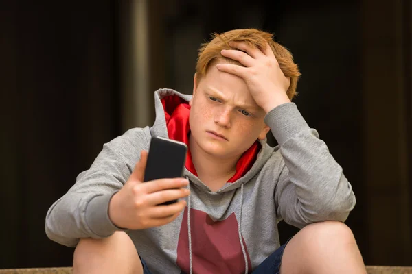 Triste chico mirando el teléfono móvil —  Fotos de Stock