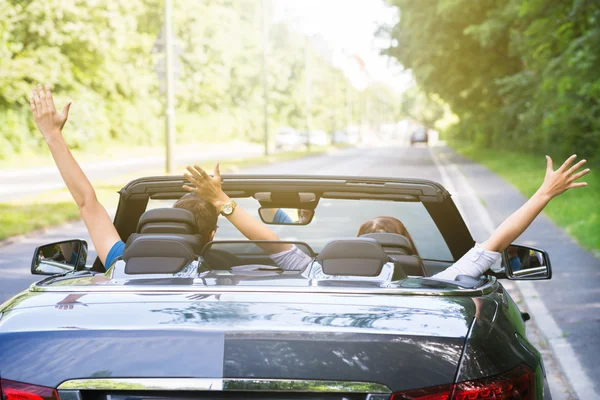 Koppel In een auto verhogen hun armen zit — Stockfoto