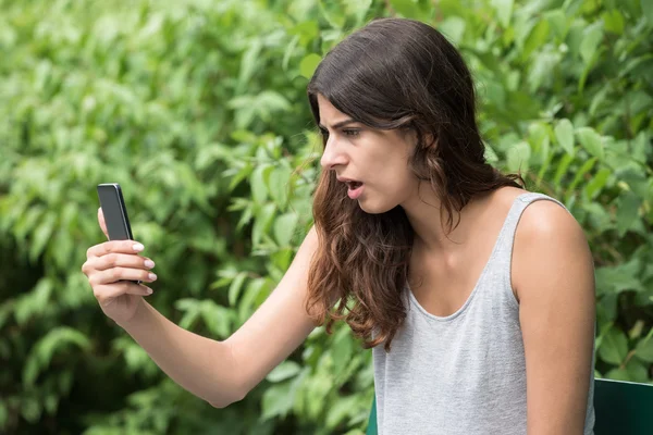 Разочарованная женщина смотрит на мобильный телефон — стоковое фото