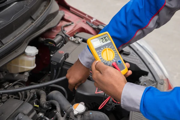 Mechaniker überprüft Batterie mit Multimeter — Stockfoto