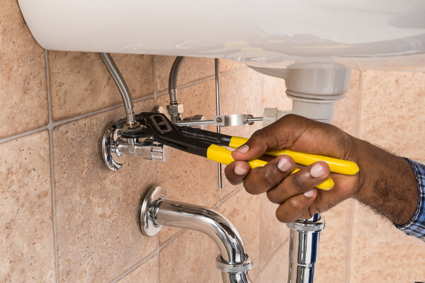 Plumber's Hand Repairing Sink In Bathroom