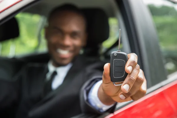 Homme d'affaires assis dans une voiture montrant la clé de la voiture — Photo